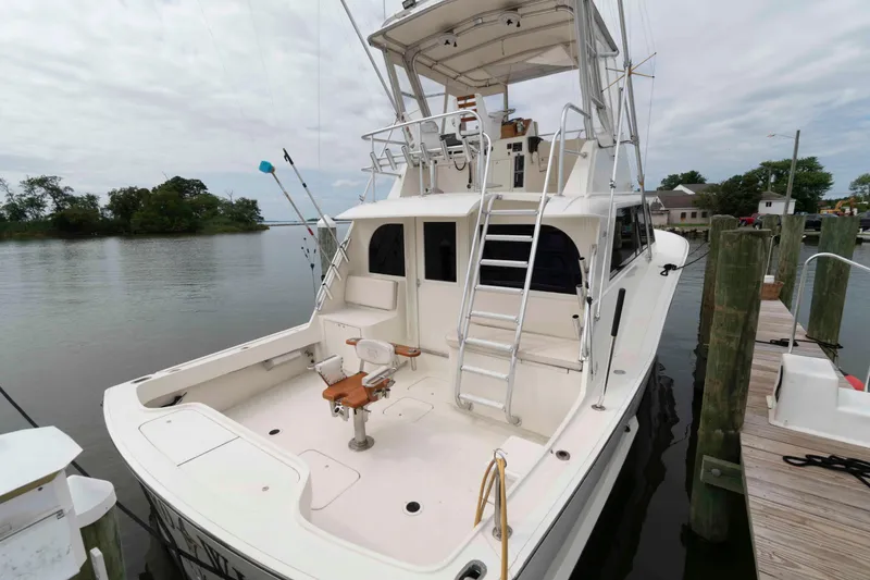 Slide: The Image of 1970 Hatteras 45 Convertible yacht docked, featuring spacious deck and ladder to upper helm. - 1