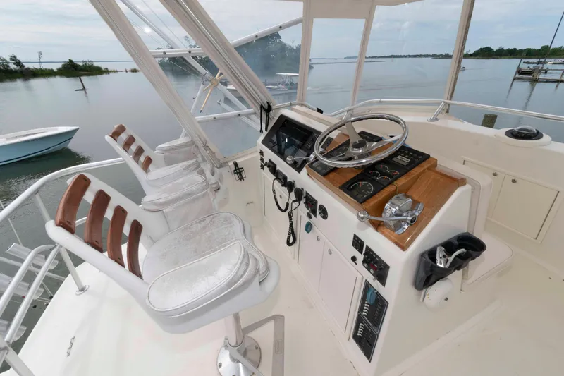 Slide: The Image of Helm of 1970 Hatteras 45 Convertible yacht with steering wheel and controls, overlooking serene waters. - 5