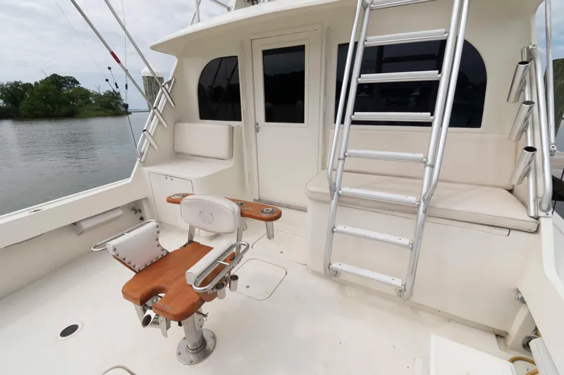 Slide: The Image of 1970 Hatteras 45 Convertible yacht cockpit with fishing chair and ladder, docked by water. - 3