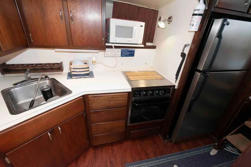 Slide: The Image of 1970 Hatteras 45 Convertible yacht kitchen with wooden cabinets, stove, microwave, and refrigerator. - 17