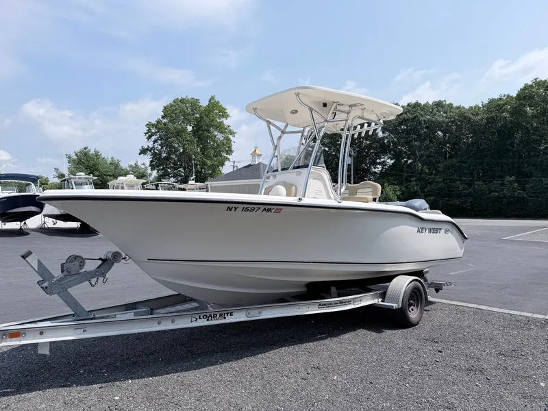 Slide: The Image of A 2014 Key West 219 FS boat on a trailer, parked on a paved lot. - 2