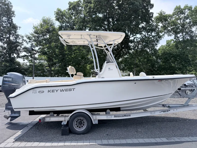 Slide: The Image of A 2014 Key West 219 FS boat on a trailer, surrounded by trees. - 3