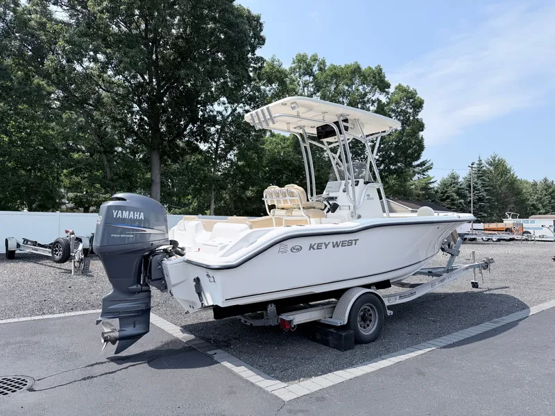 Slide: The Image of A white 2014 Key West 219 FS boat on a trailer, surrounded by trees. - 4