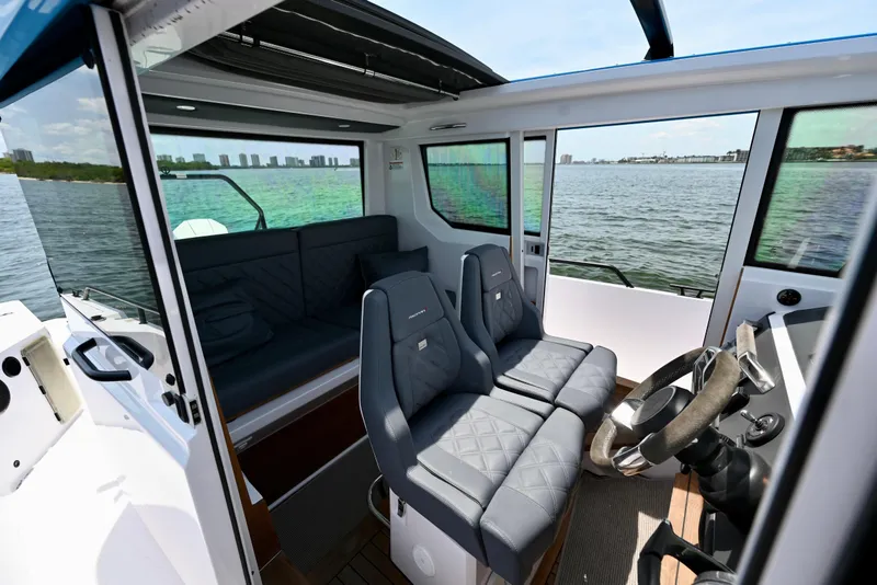 Slide: The Image of Interior of 2021 Axopar 28 Cabin boat with seating and steering, overlooking water. - 2