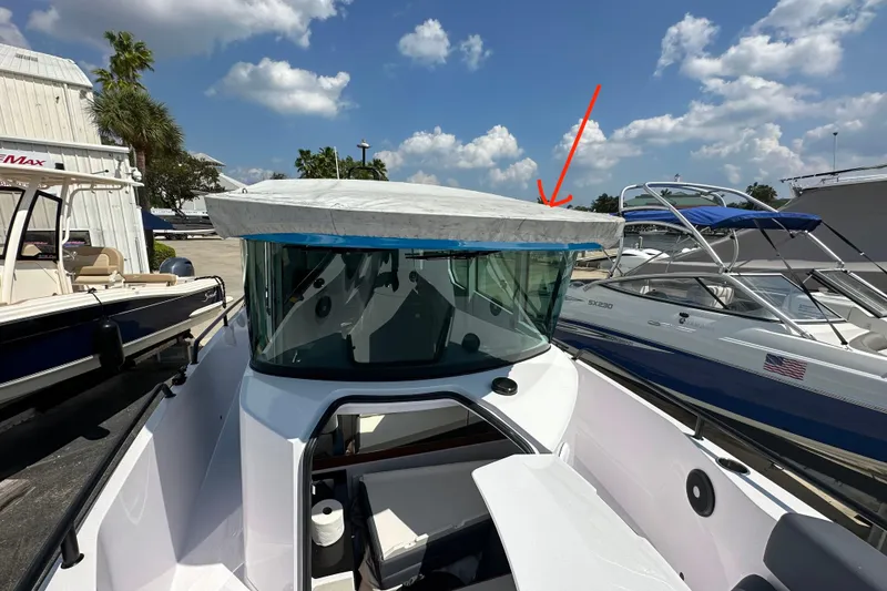 Slide: The Image of 2021 Axopar 28 Cabin boat with covered roof, docked under a sunny sky. - 7