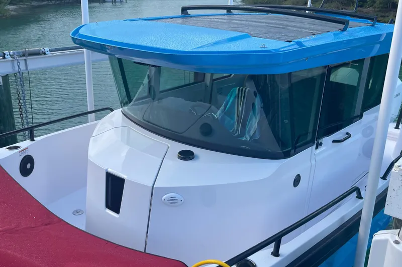 Slide: The Image of 2021 Axopar 28 Cabin boat with blue roof, docked by the water. - 6