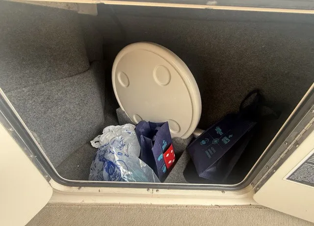 Slide: The Image of A storage compartment inside a boat with bags and a round lid. - 16