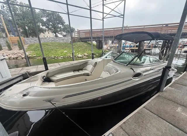 Slide: The Image of A 2006 Sea Ray 240 Sundeck is docked under a canopy. It features a black bimini top. - 8