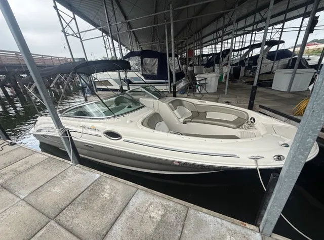 Slide: The Image of A 2006 Sea Ray 240 Sundeck is docked in a covered marina. It features an open deck and a Bimini top. - 6