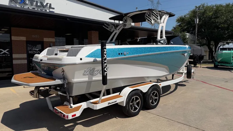 Slide: The Image of A 2021 Tigé Z3 boat on a trailer, parked in front of a building. It features a blue and white paint job. - 3