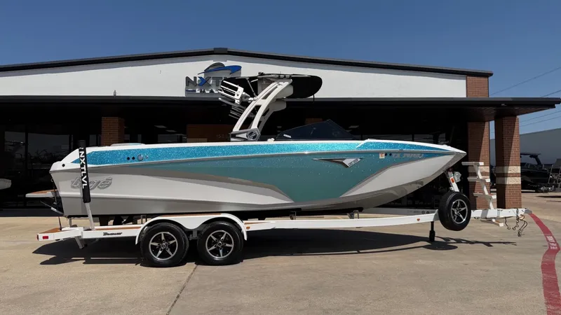 The Image of A 2021 Tigé Z3 boat on a trailer in front of a building. It features a turquoise and white paint job. - 1