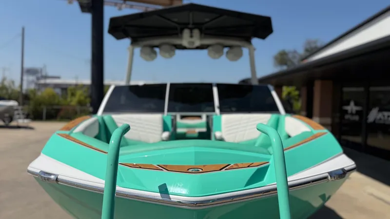 Slide: The Image of A turquoise boat with white seats and a black canopy is parked on a lot. - 8
