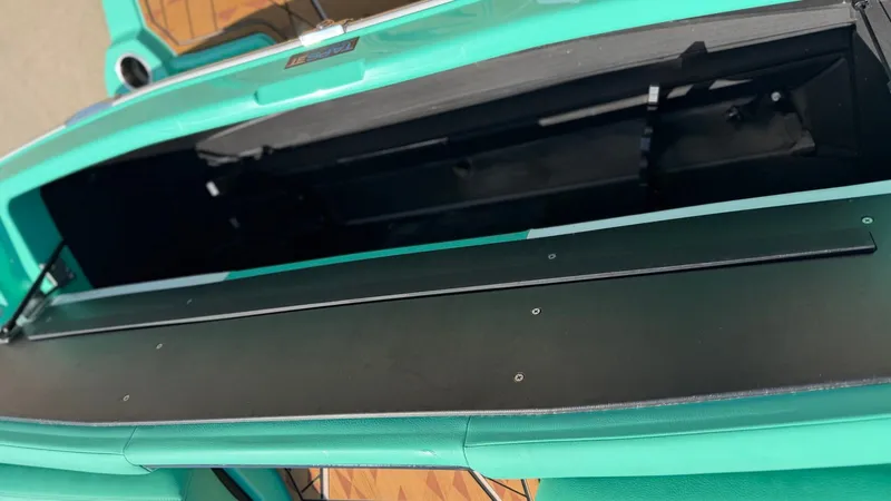 Slide: The Image of An open storage compartment on a boat with turquoise upholstery. - 32