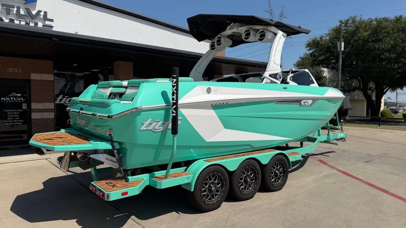 Slide: The Image of A turquoise 2025 Tigé Ultré 23ZX boat on a trailer outside a building. - 3