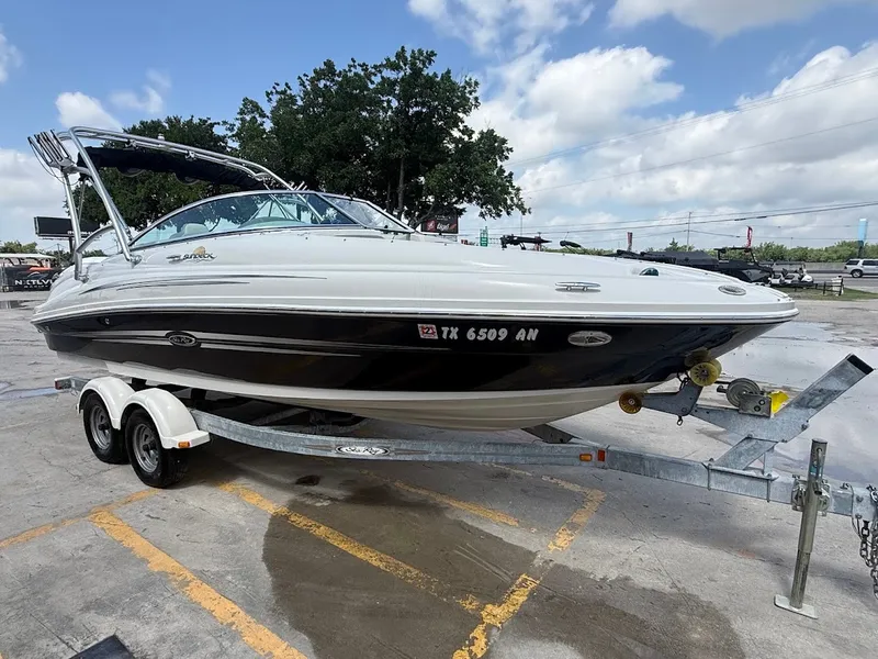 Slide: The Image of A white and black 2007 Sea Ray 220 Sundeck boat on a trailer outdoors. - 7