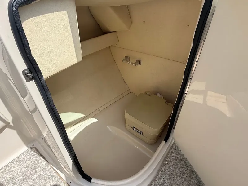 Slide: The Image of A compact beige toilet area on a boat with a portable toilet and a towel holder. - 21