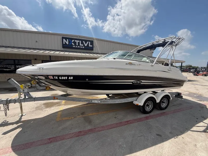 The Image of A white 2007 Sea Ray 220 Sundeck boat on a trailer in front of a building. - 1