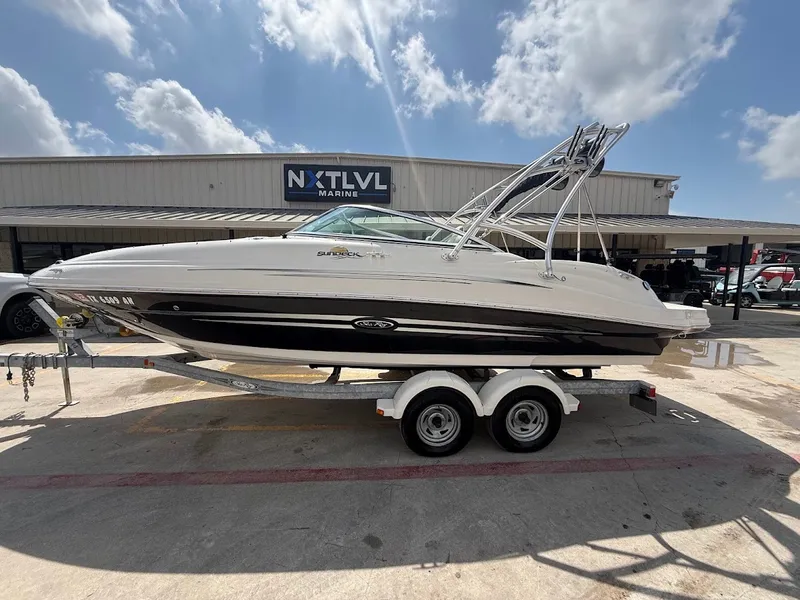 Slide: The Image of A white and black 2007 Sea Ray 220 Sundeck boat on a trailer in front of a building. - 2