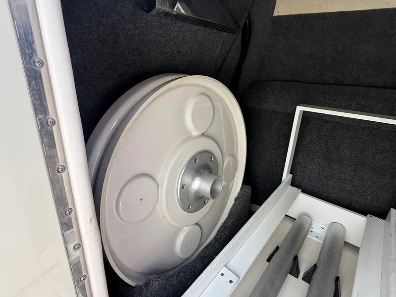 Slide: The Image of A white boat part in a carpeted storage area, possibly a spare wheel. - 22