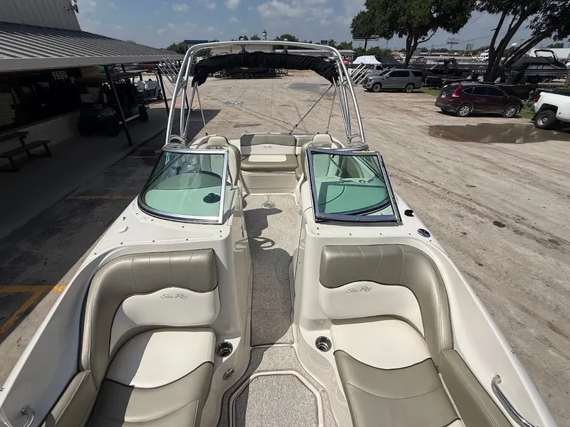 Slide: The Image of A 2007 Sea Ray 220 Sundeck with beige seating and a bimini top, parked in a lot. - 26