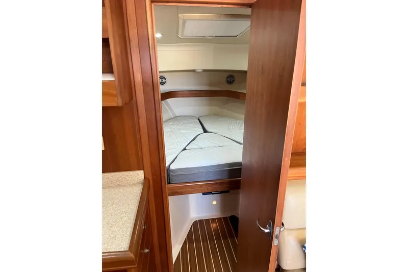 Slide: The Image of 2007 Mainship Pilot 34 Sedan cabin interior with cozy bed and wooden finishes. - 12