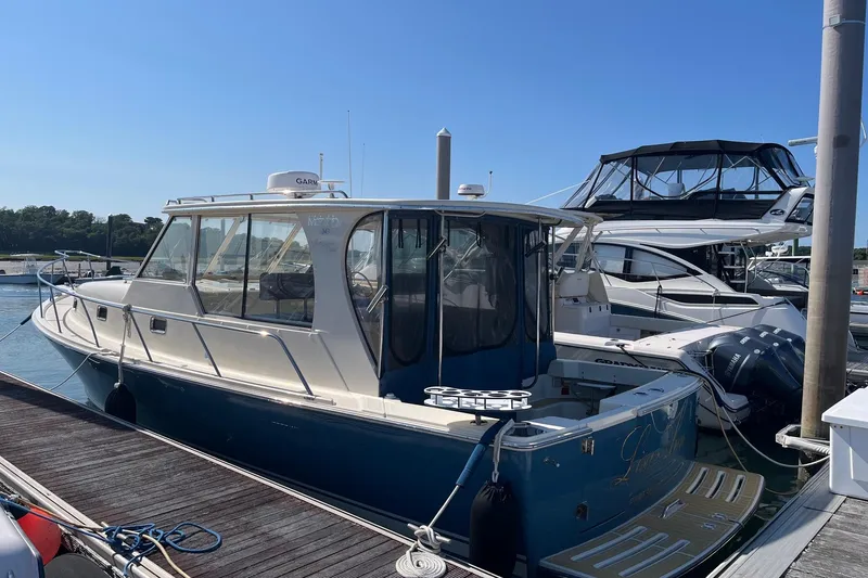 The Image of A 2007 Mainship Pilot 34 Sedan docked. It features a blue hull and white upper deck. - 1