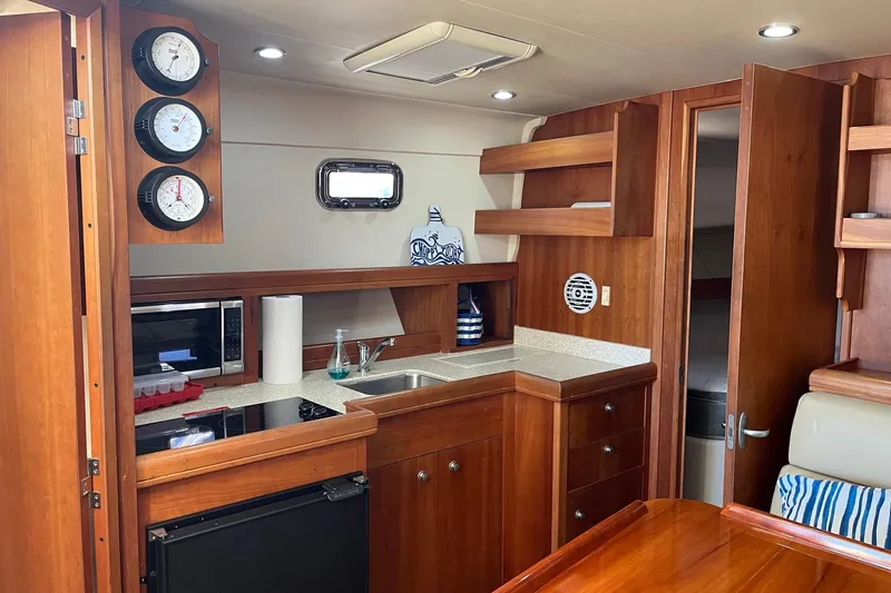 Slide: The Image of 2007 Mainship Pilot 34 Sedan interior with kitchen, wood cabinetry, and nautical decor. - 14