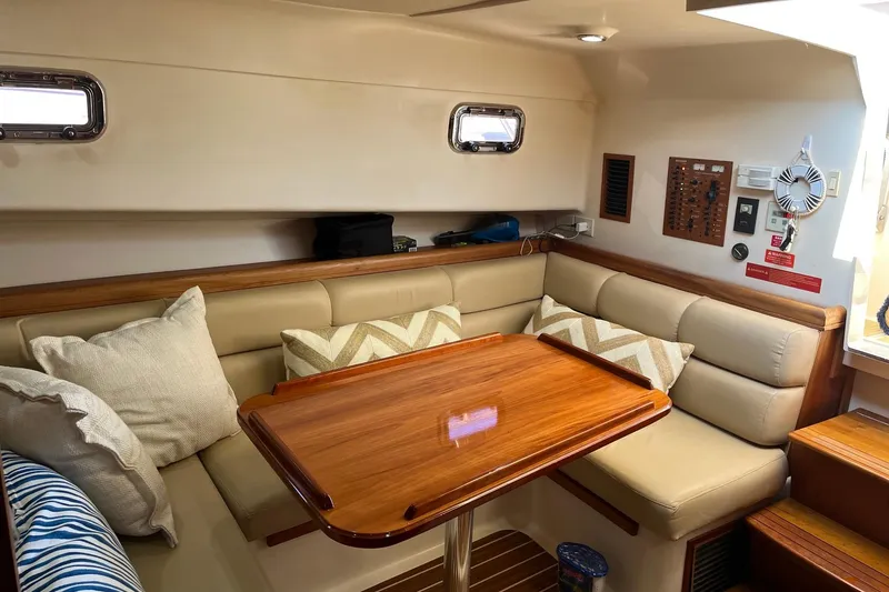 Slide: The Image of 2007 Mainship Pilot 34 Sedan interior with cozy seating and polished wooden table. - 9