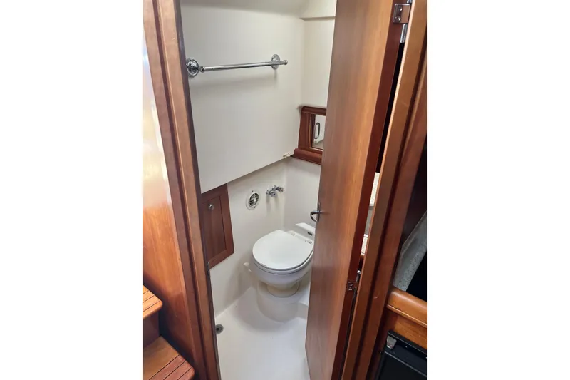 Slide: The Image of 2007 Mainship Pilot 34 Sedan bathroom with wooden door and compact toilet. - 13