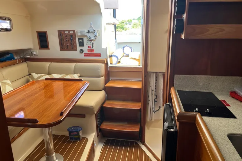 Slide: The Image of Interior of 2007 Mainship Pilot 34 Sedan with wooden table and compact kitchen area. - 8