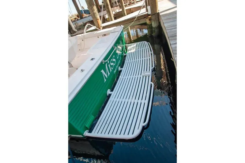 Slide: The Image of 2004 Cabo 40 Express boat docked, featuring a green hull and white swim platform. - 16