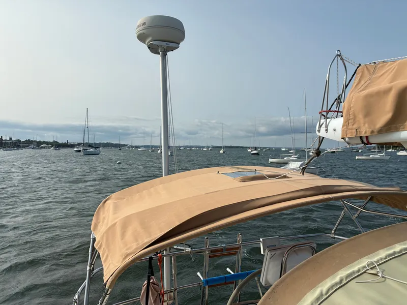 Slide: The Image of A sailboat with a beige canopy is anchored in a busy harbor. - 20