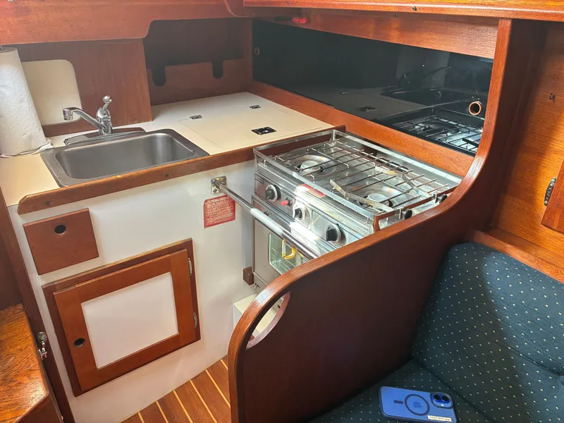 Slide: The Image of The galley of a 1986 Freedom Yachts 30 with a sink, stove, and wood paneling. - 30