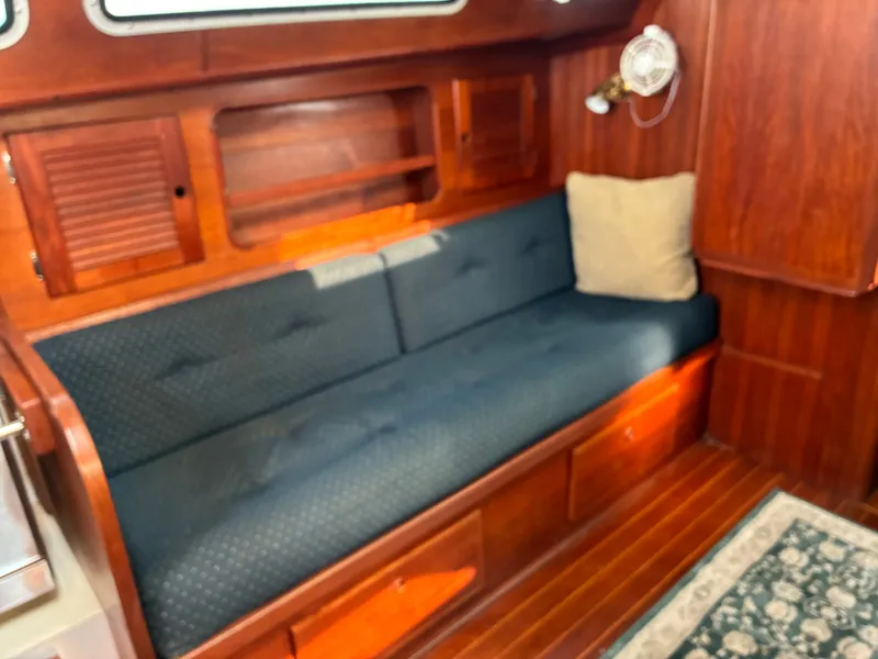 Slide: The Image of The interior cabin of a 1986 Freedom Yachts 30 features a cushioned bench and wooden walls. - 27