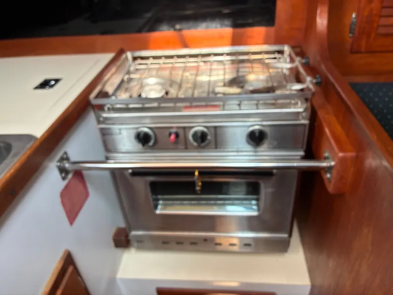 Slide: The Image of A stainless steel stove with three knobs and an oven in a boat's galley. - 31