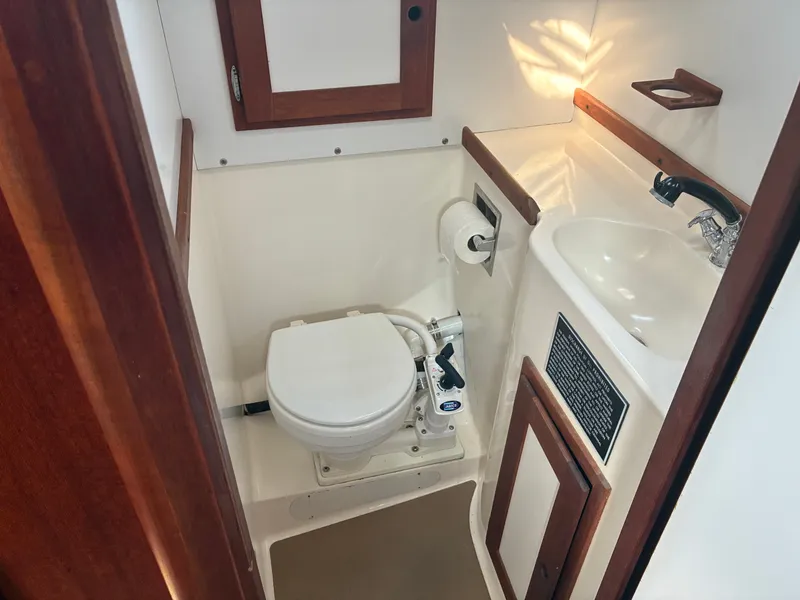 Slide: The Image of The image shows a clean yacht bathroom with a toilet, sink, and wooden trim. - 38