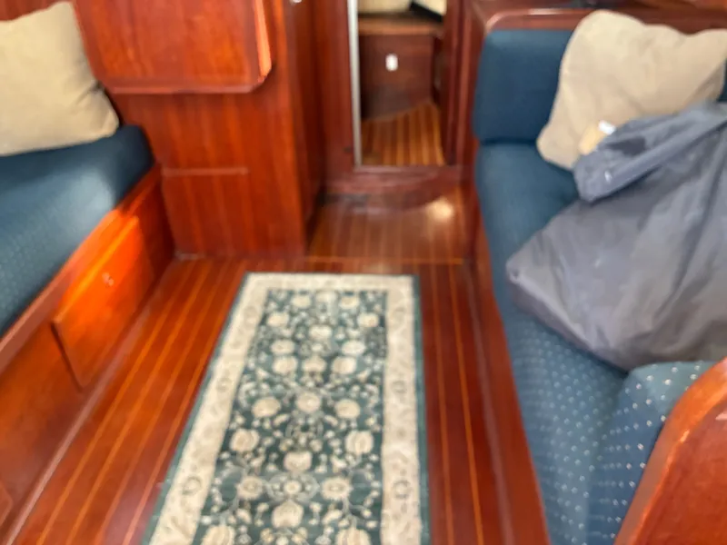 Slide: The Image of Interior of a yacht with wooden flooring, blue upholstery, and a patterned rug runner. - 25