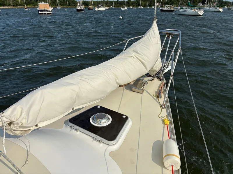 Slide: The Image of A 1986 Freedom Yachts 30 sailboat is anchored on the water, with a covered sail on deck. - 15