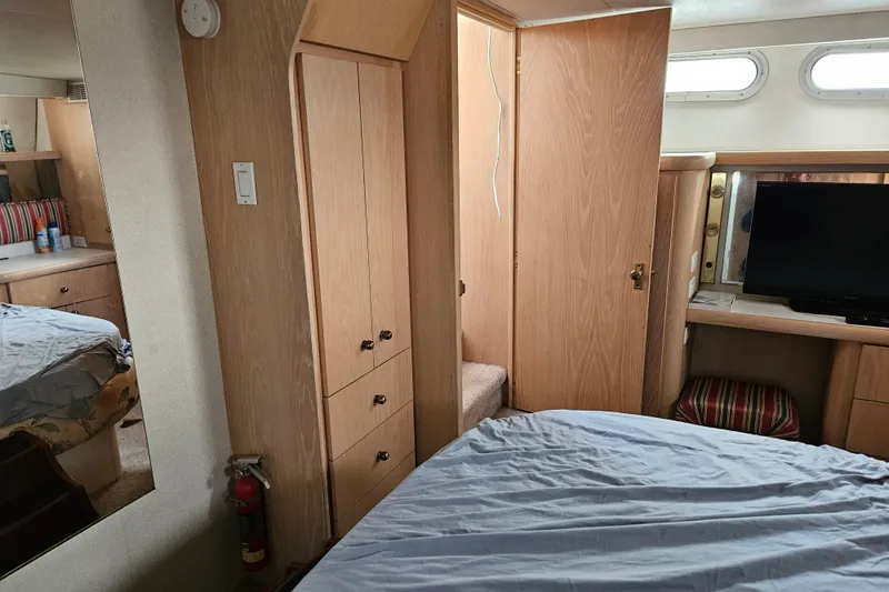 Slide: The Image of Interior of 1993 Silverton 46 Motor Yacht with bed, TV, and wooden cabinetry. - 42