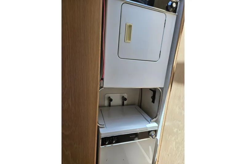 Slide: The Image of Laundry area inside a 1993 Silverton 46 Motor Yacht, featuring a compact washer and dryer. - 23