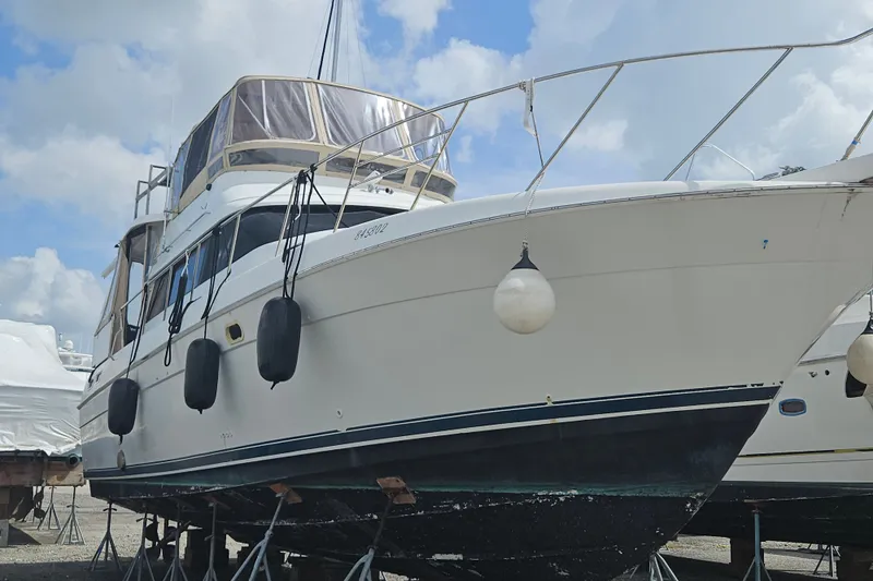Slide: The Image of 1993 Silverton 46 Motor Yacht on stands, with fenders, under a cloudy sky. - 57