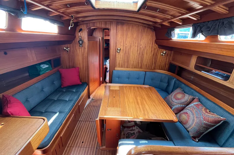Slide: The Image of Cozy interior of a 1984 Vindo 34 sailboat with wooden paneling and cushioned seating. - 4