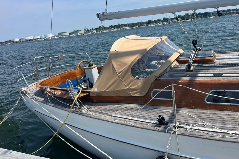 Slide: The Image of 1984 Vindo 34 sailboat docked, featuring wooden deck and beige canopy, on a sunny day. - 9