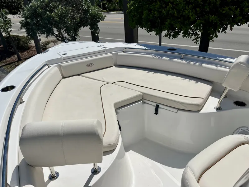 Slide: The Image of 2022 Sea Hunt Ultra 234 with beige bow seating, surrounded by trees and a road. - 17