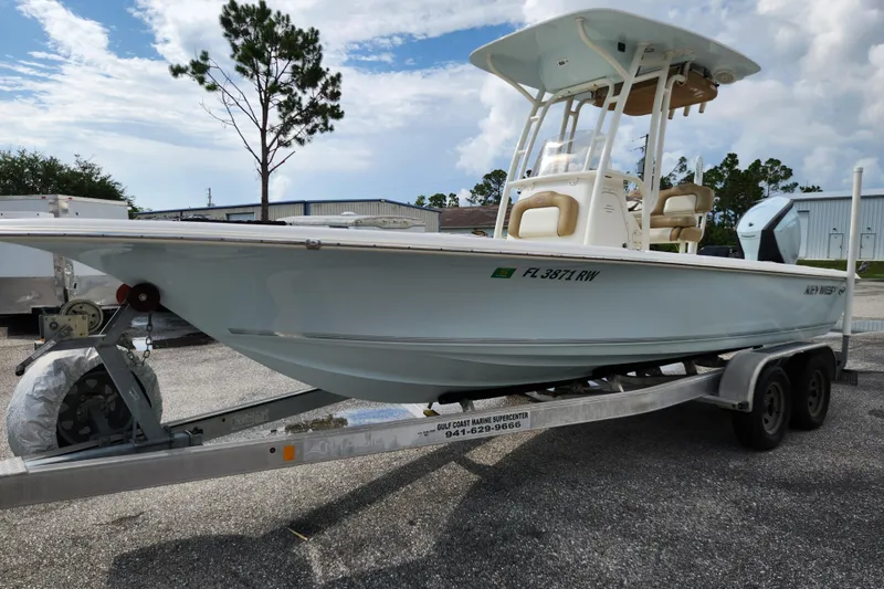 Slide: The Image of 2019 Key West 230 Bay Reef boat on trailer, parked outdoors under cloudy sky. - 3