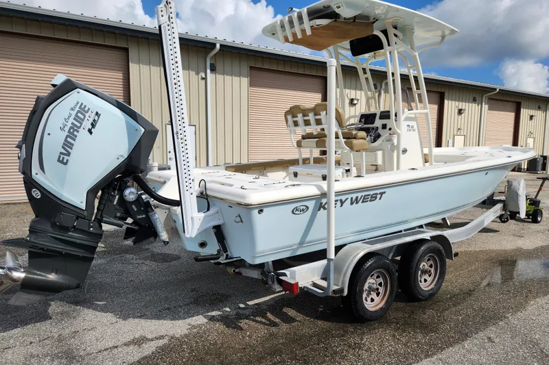 Slide: The Image of 2019 Key West 230 Bay Reef boat with Evinrude engine on trailer, parked outdoors. - 1