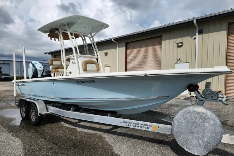 Slide: The Image of 2019 Key West 230 Bay Reef boat on trailer, parked outside industrial building. - 2