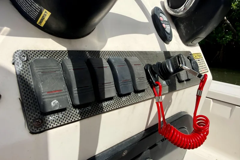 Slide: The Image of Control panel of a 2007 Hewes Redfisher 21 boat with switches and safety lanyard. - 12