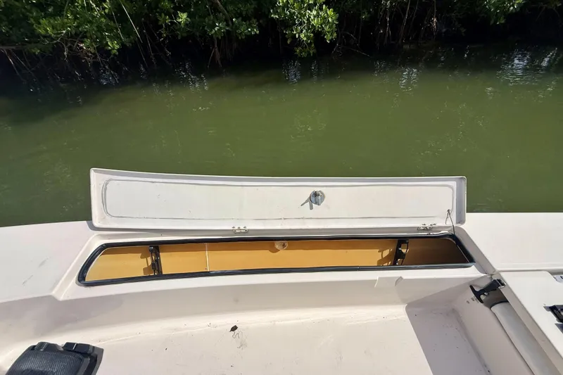 Slide: The Image of Open storage compartment on 2007 Hewes Redfisher 21 boat near water and greenery. - 17
