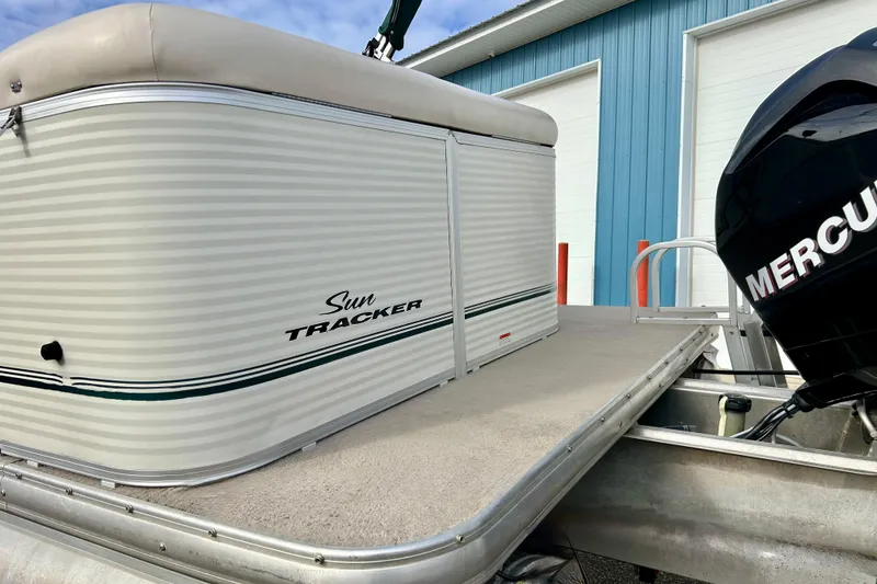 Slide: The Image of 2010 Sun Tracker Party Barge 20 Classic Series with Mercury engine, docked near blue building. - 16